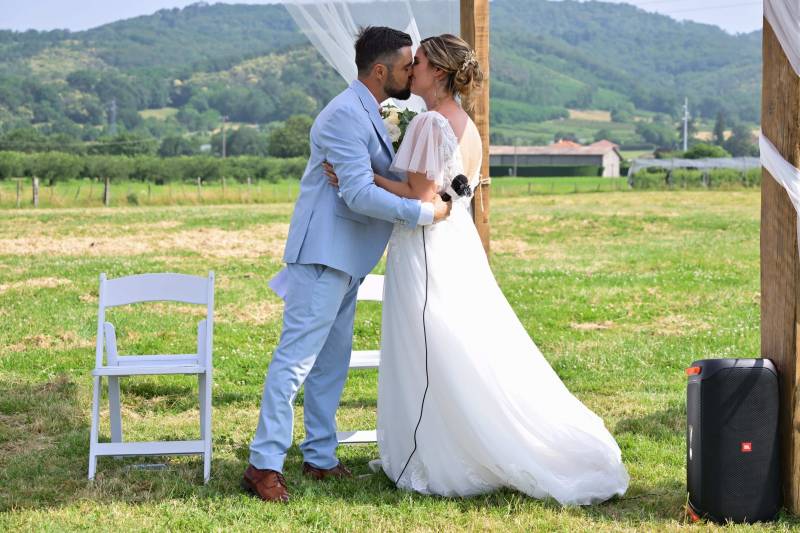 Photo naturelle du baiser des mariés pendant une cérémonie laïque en extérieur